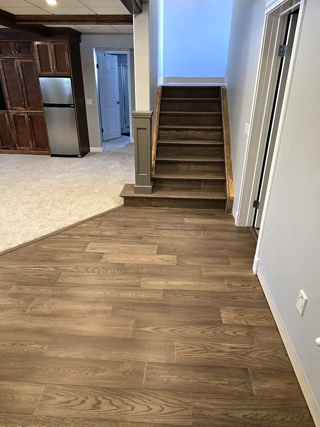 Basement staircase with a carpeted floor and wood landing