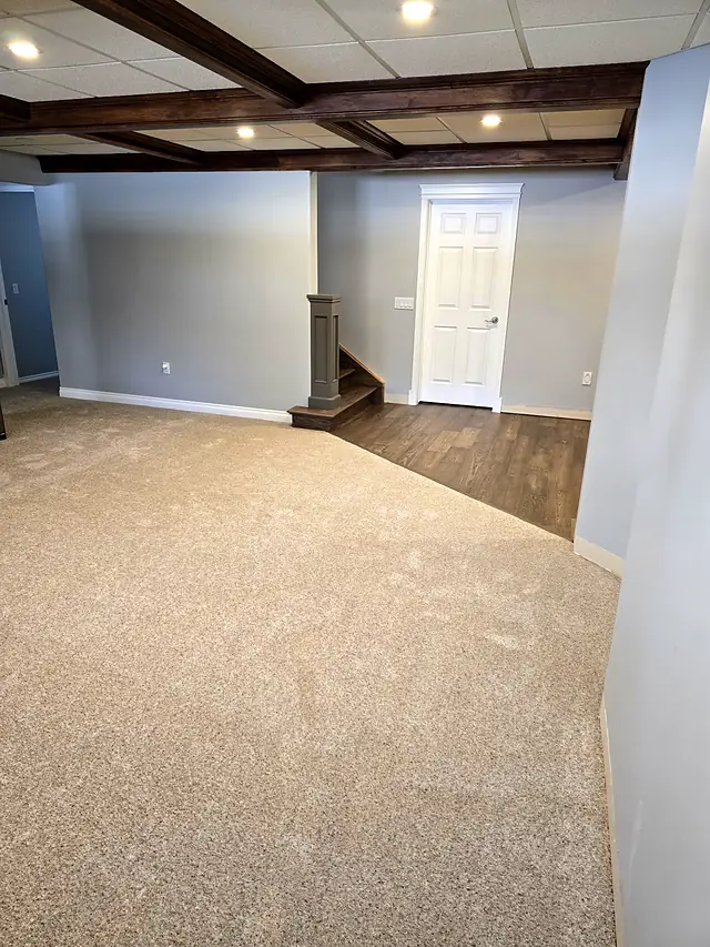 Carpeted basement with a beamed ceiling